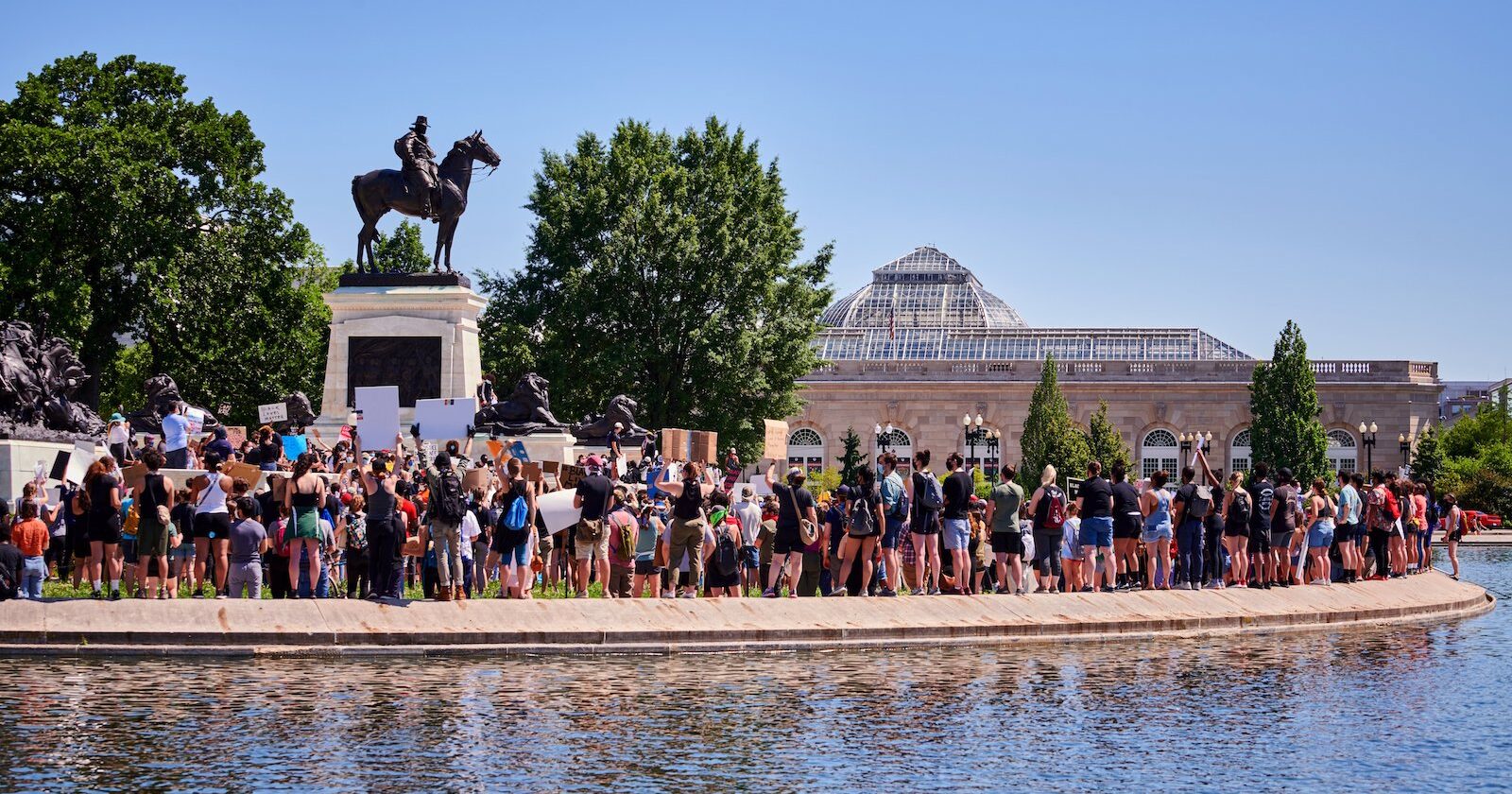 Group of protestors standing under monument in Washington, DC