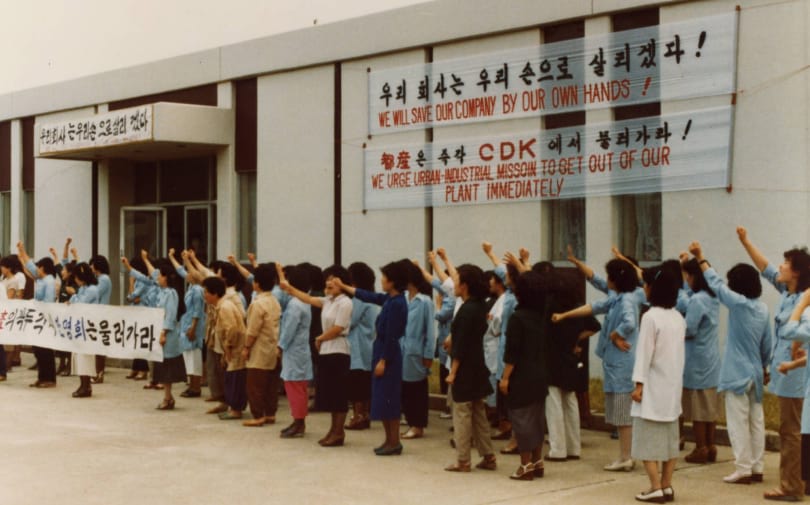 Several people protesting outside of a building