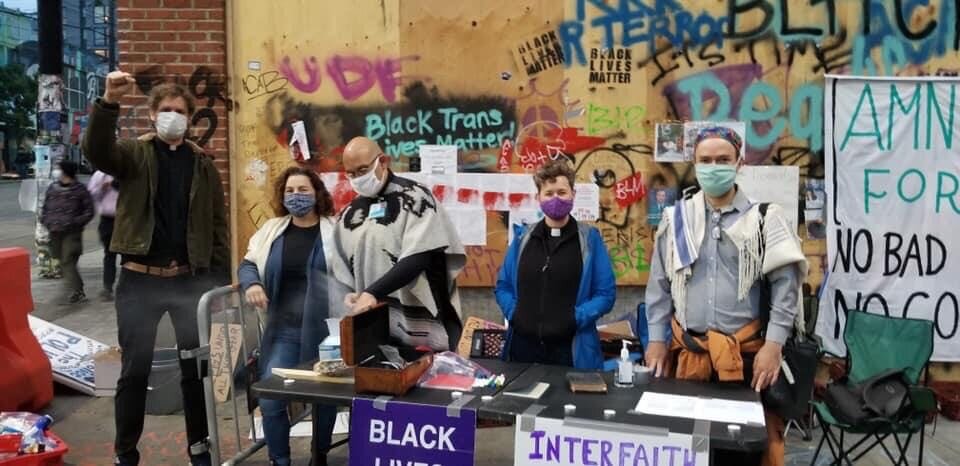 This photo shows a group of interfaith clergy outside ministering to protesters