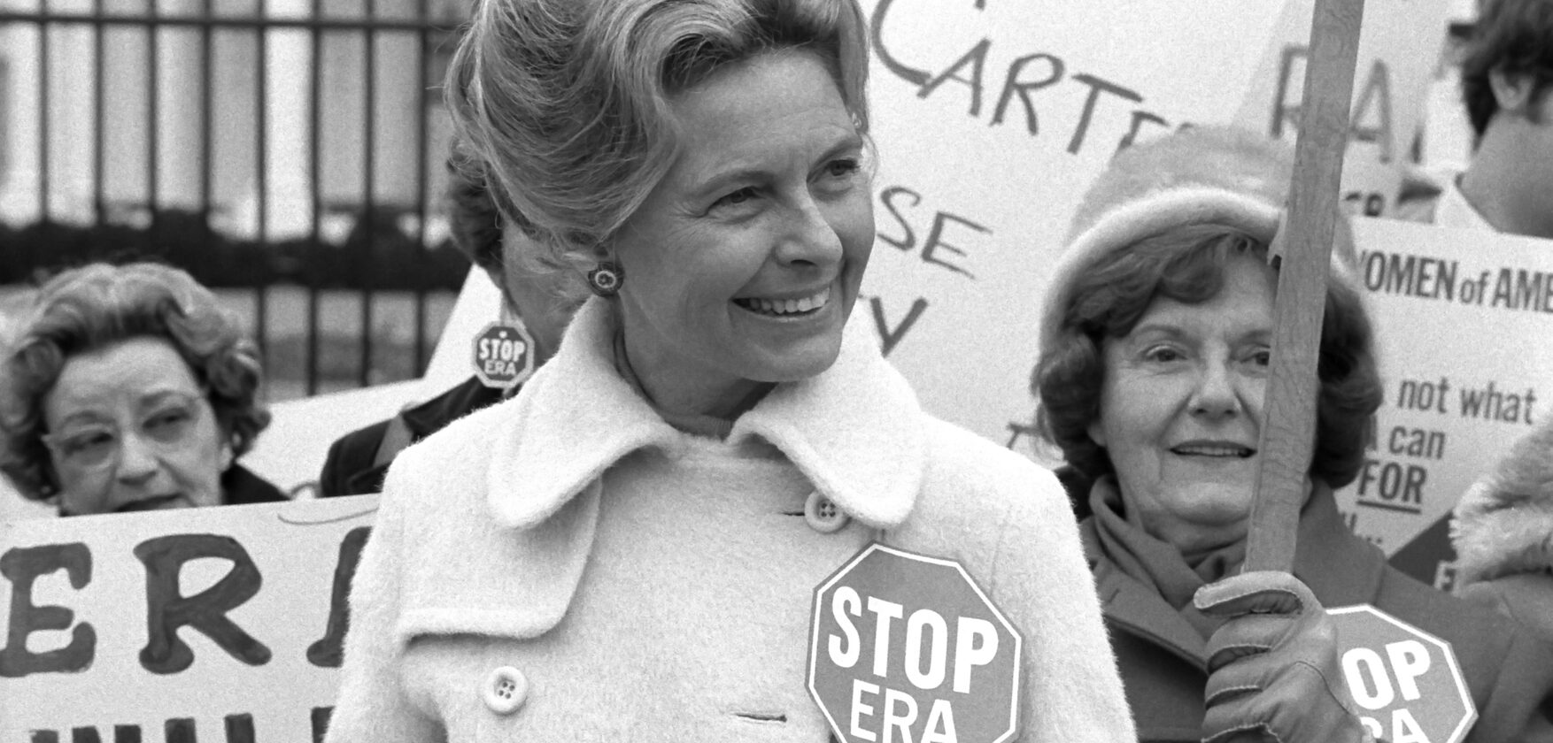 This is an image of activist Phyllis Schafly with women behind her holding picket signs.