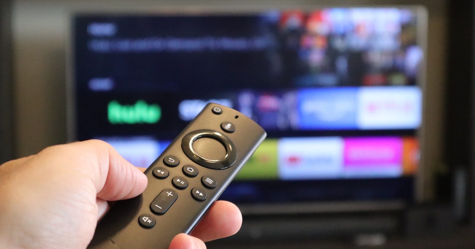 Hand holding remote control in front of TV Screen