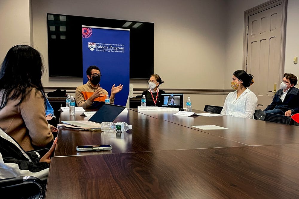 Students are sitting around a table in a board room . Three individuals are looking to the center of the room at a person speaking.
