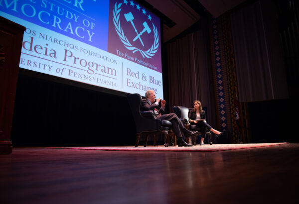 John Bolton sitting next to Lexi Boccuzzi on a stage.