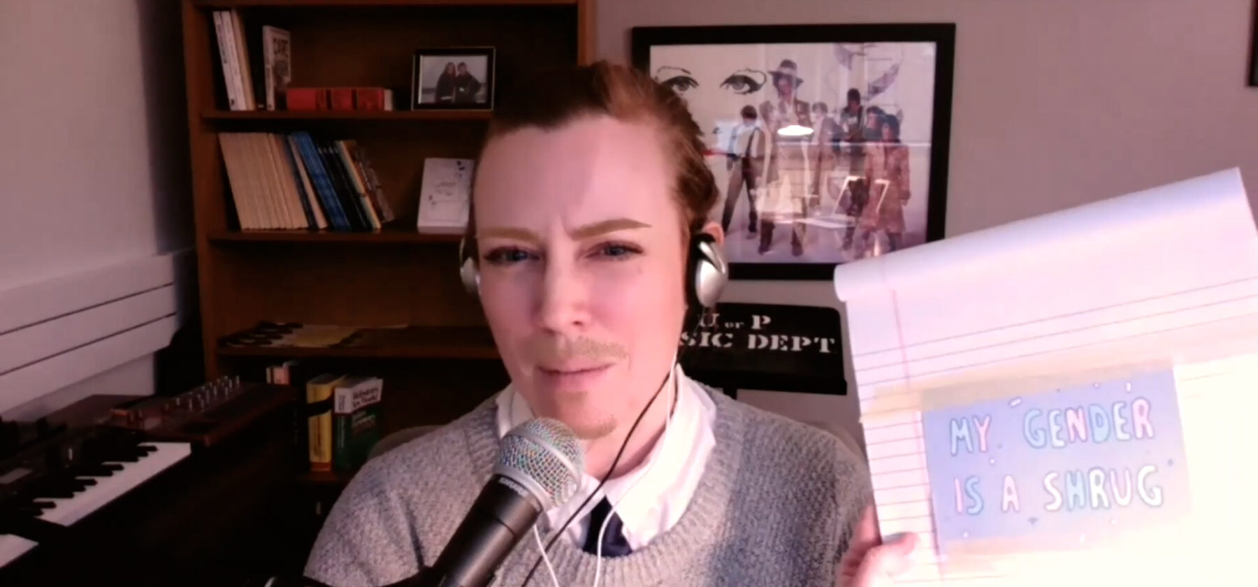 Panelist on Zoom event holding up a piece of paper that says "my gender is a shrug"