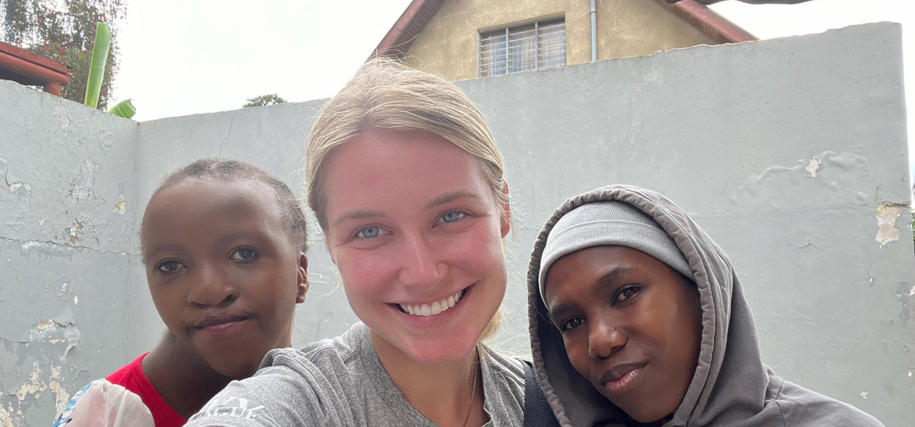 Three women standing in front of a concrete wall in Tanzania