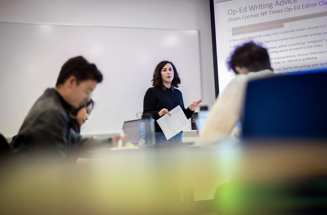 Professor in front of whiteboard with students in classroom.