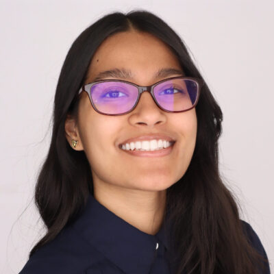 Headshot of woman with long dark hair smiling at camera wearing navy shirt