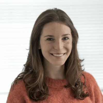 woman with light skin, long light brown hair wearing an orange wool sweater